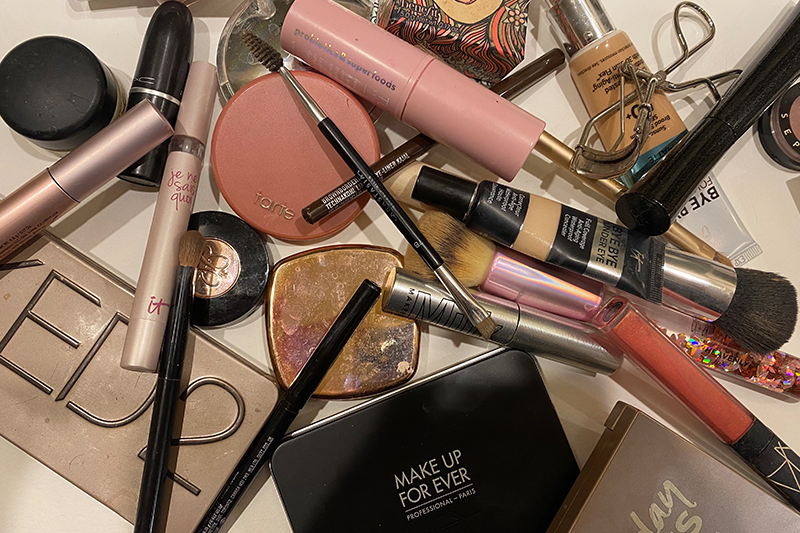 mascara, foundation, lipstick, blush, powder in a messy unorganized pile